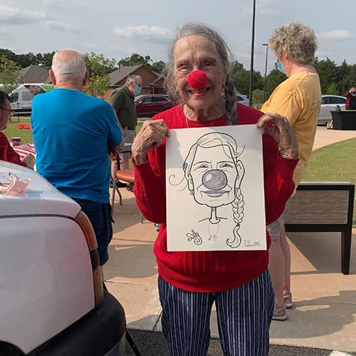 woman with clown nose holding caricature